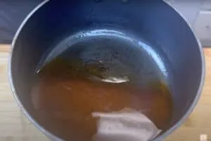 Pot with rich brown broth, perfect for soups or stews, on a wooden surface.